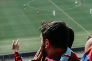 Bārdains vīrietis skatās futbola spēli