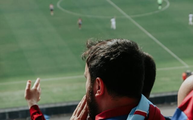 Bārdains vīrietis skatās futbola spēli