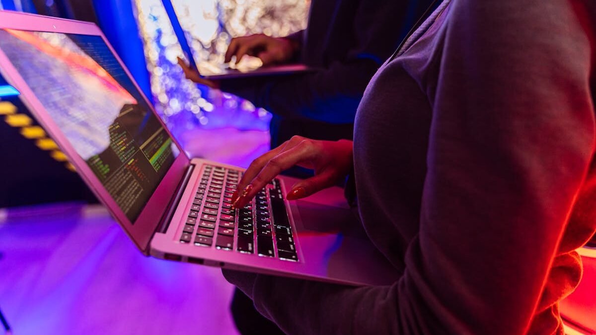 Persona melnā kreklā ar garām piedurknēm izmanto Macbook Pro
