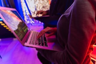 Persona melnā kreklā ar garām piedurknēm izmanto Macbook Pro