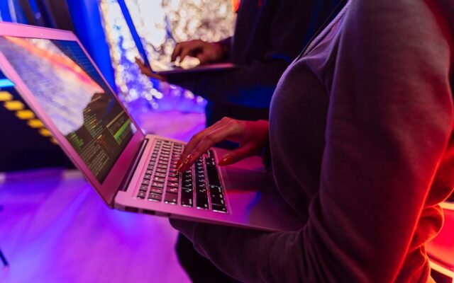 Persona melnā kreklā ar garām piedurknēm izmanto Macbook Pro