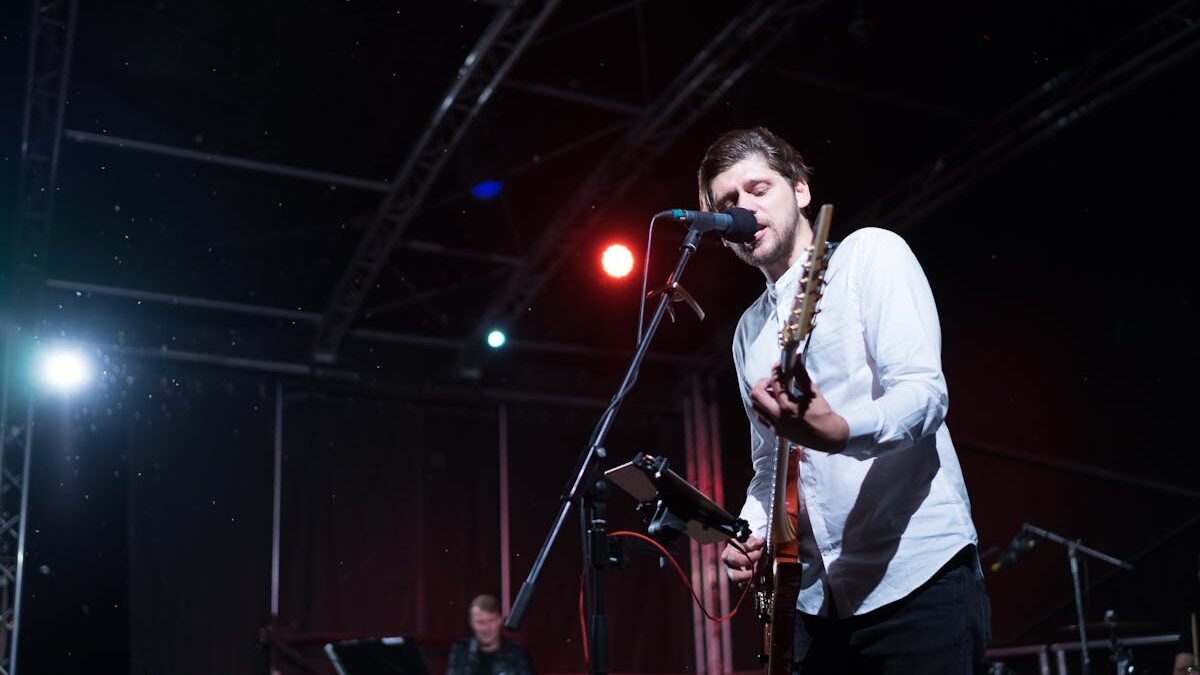Man Playing an Electric Guitar while Singing on Stage