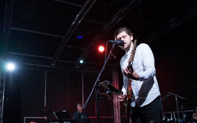 Man Playing an Electric Guitar while Singing on Stage