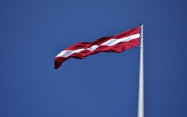 Red and White State Flag Waving Under Blue Sky at Daytime