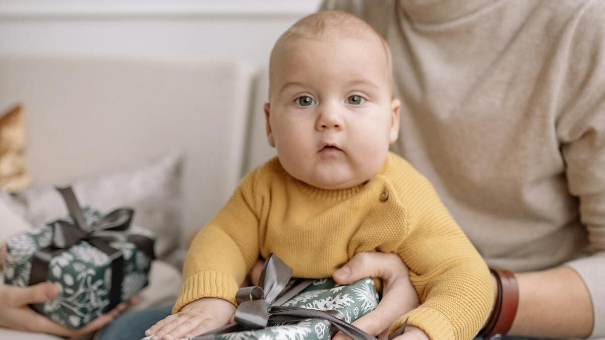 Mazulis sēž tēvam klēpī un tur dāvanu