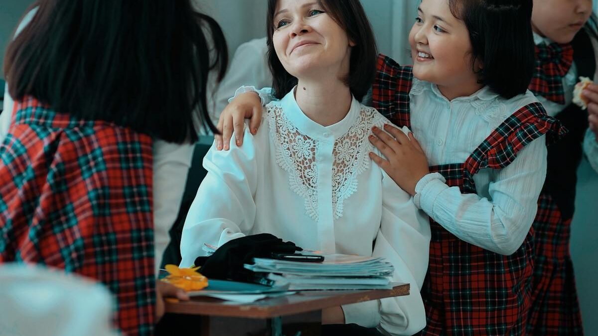 Skolnieces ap skolotāju sēž pie galda