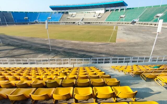Tukšs stadions ar krāsainiem sēdekļiem saulainā dienā