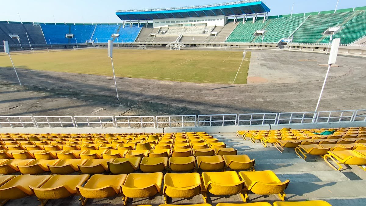Tukšs stadions ar krāsainiem sēdekļiem saulainā dienā