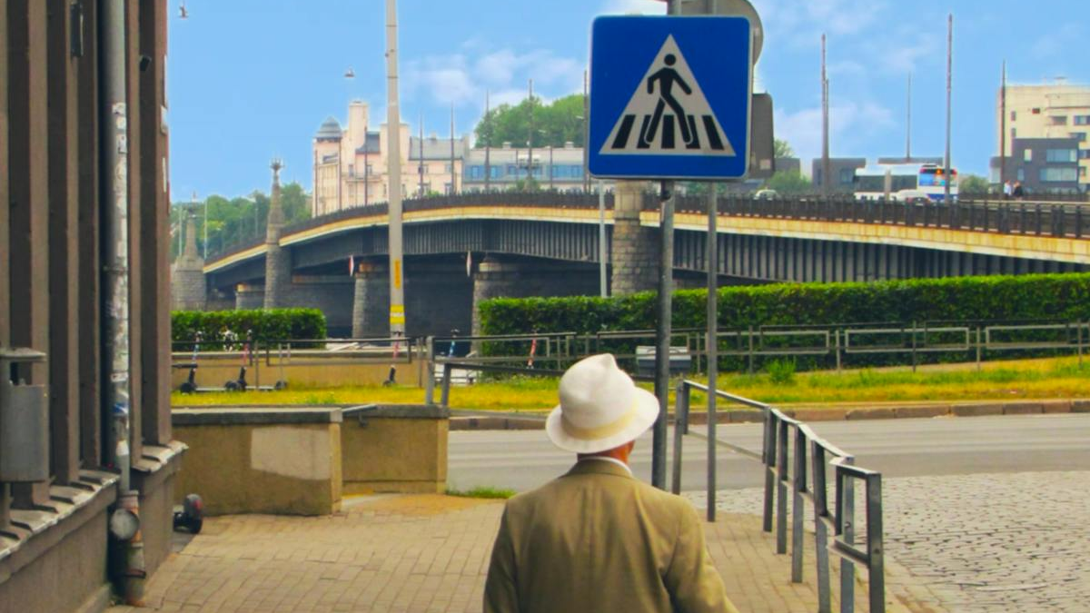 Gados vecāks ceļotājs Rīgas ielā ar Latvijas karogu
