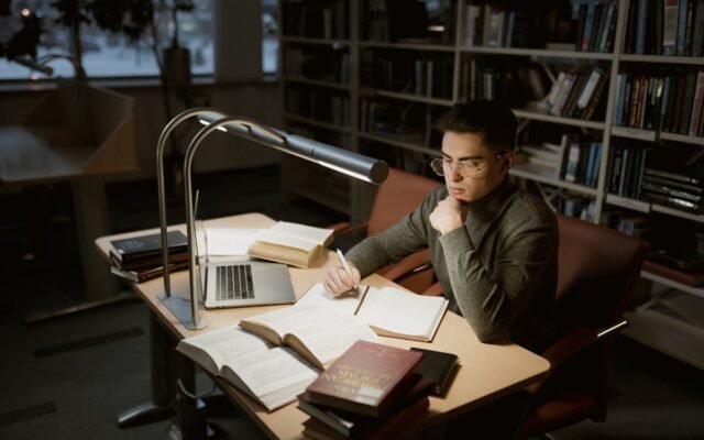 Vīrietis lasa bibliotēkā